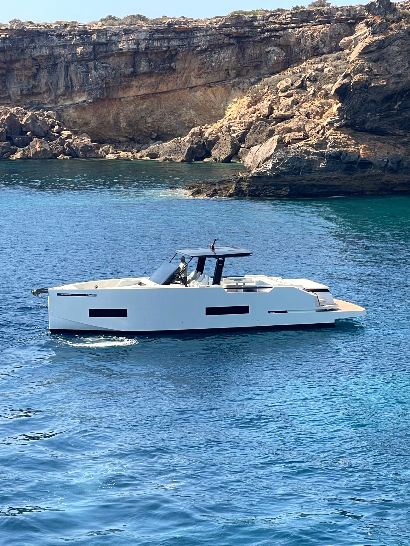 Approaching a beach club by sea, the coastline of Camp de Mar opening ahead.